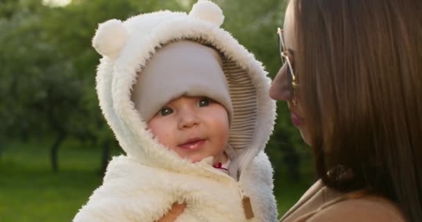 Penembakan jarak dekat. Bayi itu tersenyum dan bersandar terhadap ibunya. 4K — Stok Video