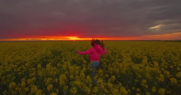 La chica feliz está saltando y corriendo sobre el terreno. puestas de sol. 4K — Vídeos de Stock
