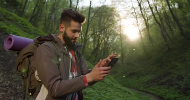 Disparos de cerca. El tipo está mirando los mapas en el teléfono inteligente. Senderismo en el bosque. 4K — Vídeos de Stock