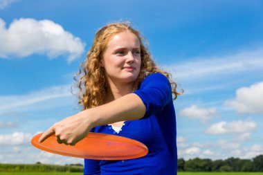 Young dutch woman throwing orange frisbee clipart