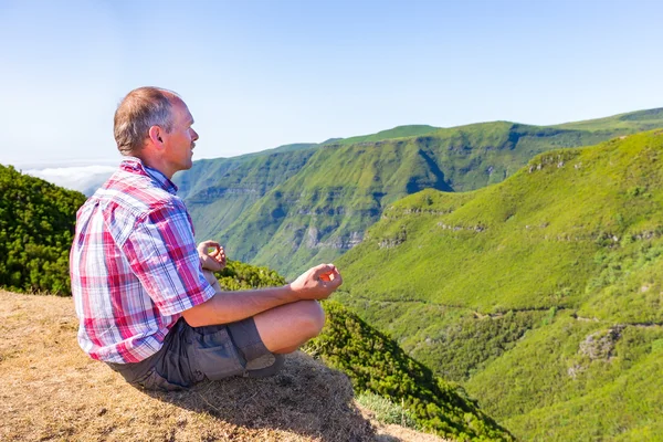 Dutch man meditating on mountain near green valley — Stock Photo, Image