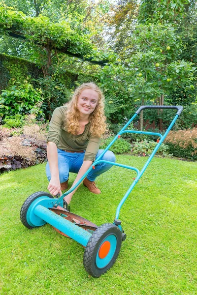 Junge Niederländerin repariert Rasenmäher im Garten — Stockfoto