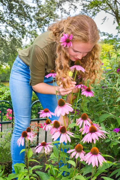 Junge kaukasische Frau riecht Echinacea-Blume im Garten — Stockfoto