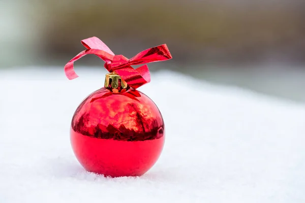 Een glanzende rode kerst bal buiten in de sneeuw — Stockfoto