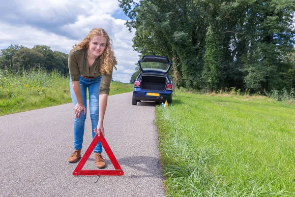 Mujer holandesa colocando triángulo de advertencia en camino rural —  Fotos de Stock
