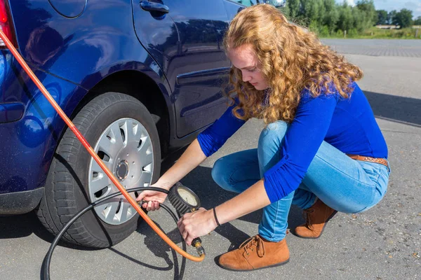 Женщина проверяет давление воздуха в шинах автомобиля — стоковое фото