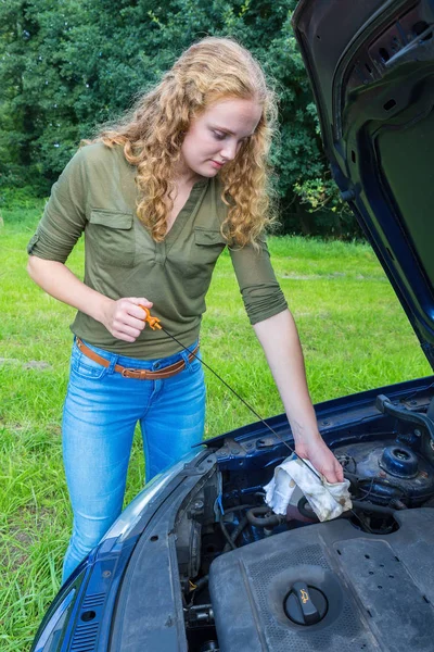 Женщина исследует уровень масла в автомобиле с помощью палочки — стоковое фото