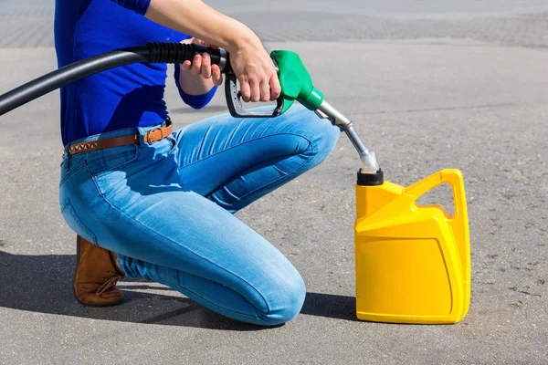 Woman filling yellow can with gasoline or petrol — Stock Photo, Image