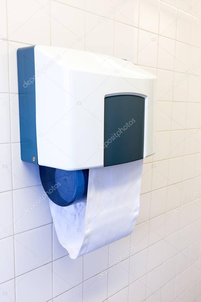 Towel dispenser hanging at tiled wall