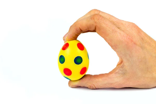 Рука держит окрашенное желтое пасхальное яйцо с точками — стоковое фото