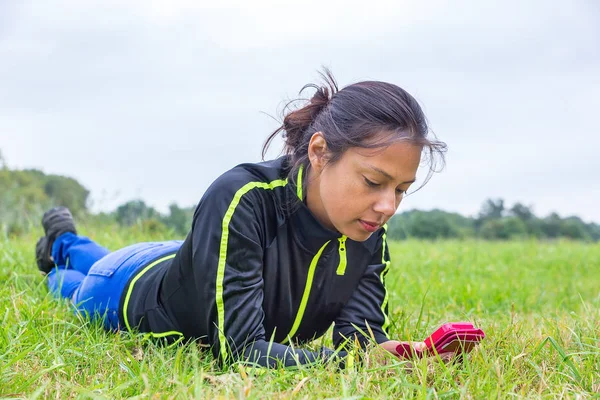 Frau liegt im Gras und bedient Handy — Stockfoto