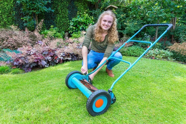 Junge Kaukasierin repariert Rasenmäher im Garten — Stockfoto