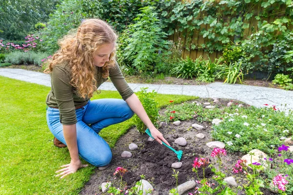 Young dutch woman raking in garden — Stock Photo, Image