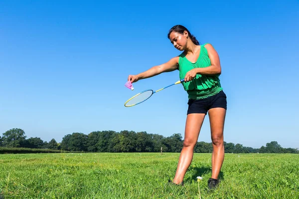 Mulher servir com badminton raquete e transporte para fora na grama — Fotografia de Stock