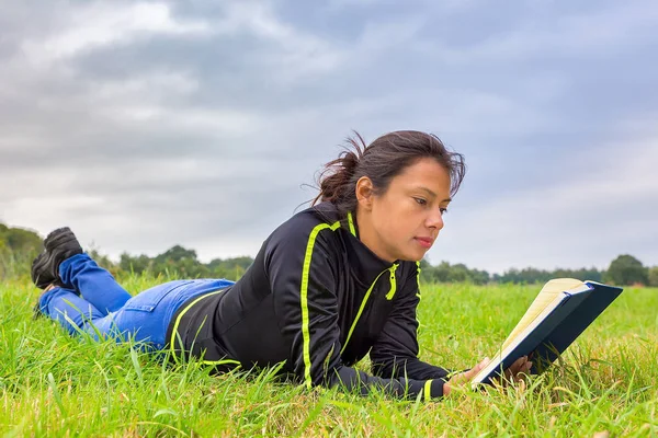 Mujer joven acostada en libro de lectura de hierba —  Fotos de Stock