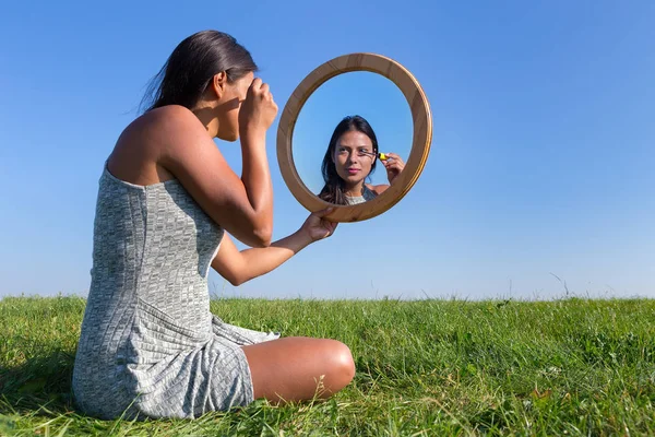 女人应用化妆品睫毛膏在外面的镜子化妆 — 图库照片