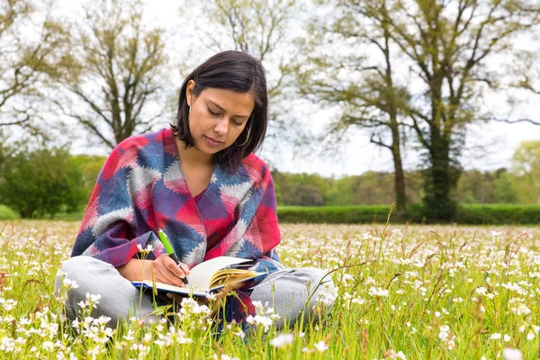 Mulher escrevendo no prado com flores da primavera — Fotografia de Stock