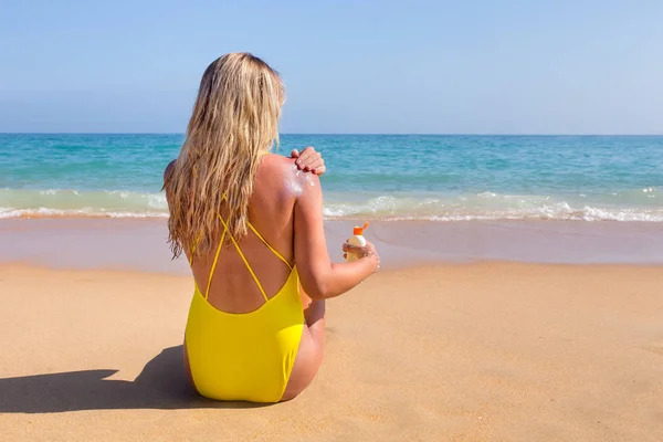 Девушка на пляже мажет солнцезащитный крем на коже — стоковое фото