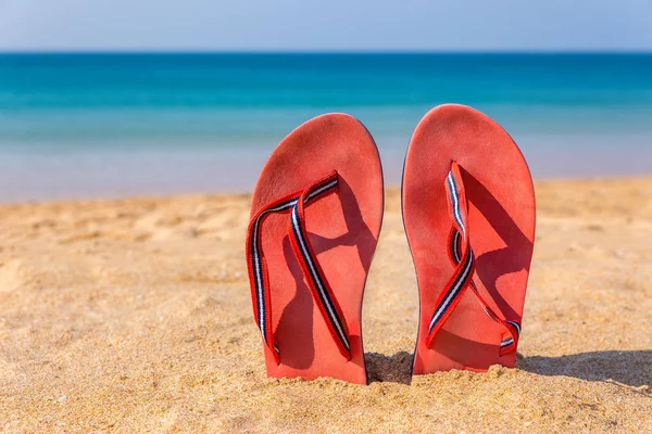 Dwa czerwone kapcie pionowo w piaszczystej plaży — Zdjęcie stockowe