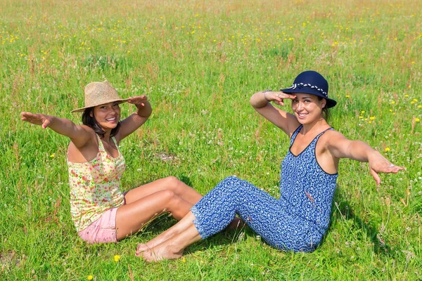 Dvě ženy, které nosí klobouky s pozdravem zelené louce — Stock fotografie