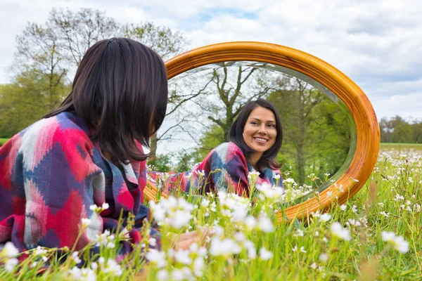 Mujer acostada con espejo en pradera floreciente — Foto de Stock