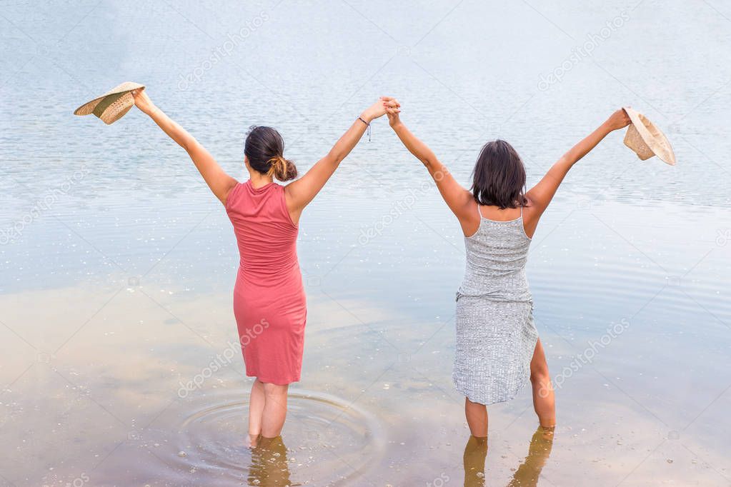 Two happy women standing in water