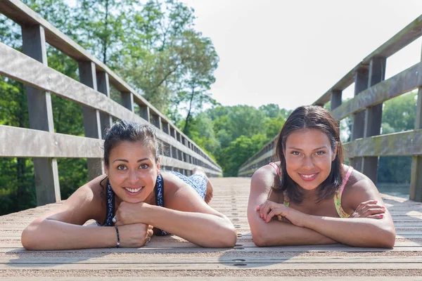 Two friends lying together on wooden bridge — Stock Photo, Image