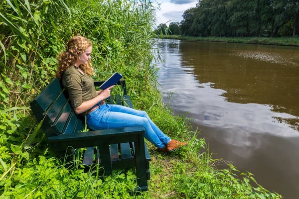 Mujer holandesa leyendo libro en el banco en el agua —  Fotos de Stock