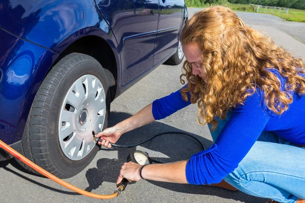 Chica comprobando la presión de aire del neumático del coche —  Fotos de Stock