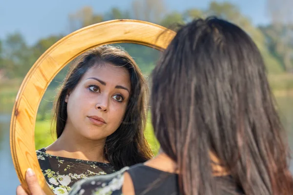 Woman looking at mirror in nature — Stock Photo, Image