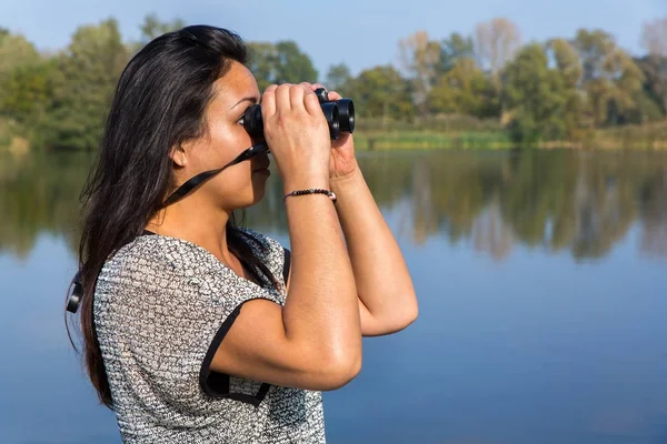 Mujer mirando a través de prismáticos en el agua — Foto de Stock