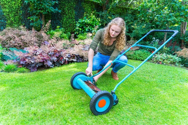 Jeune femme européenne reparing tondeuse à gazon dans le jardin — Photo