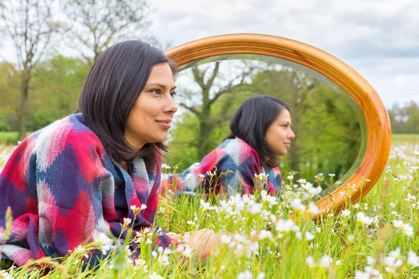 Frau liegt mit Spiegel in blühender Wiese — Stockfoto