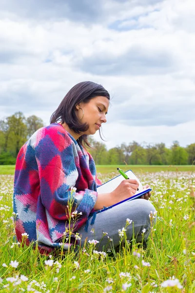 Mujer escribiendo en prado floreciente con flores de primavera —  Fotos de Stock