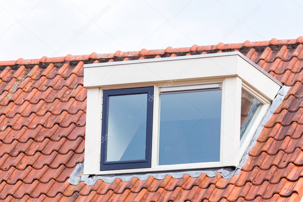 Dormer window on  roof of attic with roof tiles 