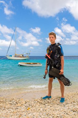 Hollandalı dalgıç deniz ve teknelerle sahilde duruyor