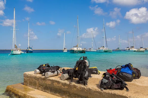 Diving equipment on coast with boats on sea — Stock Photo, Image