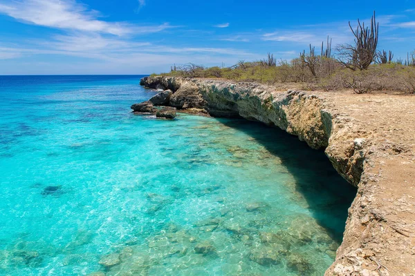 Costa rocciosa con acque poco profonde in mare blu — Foto Stock