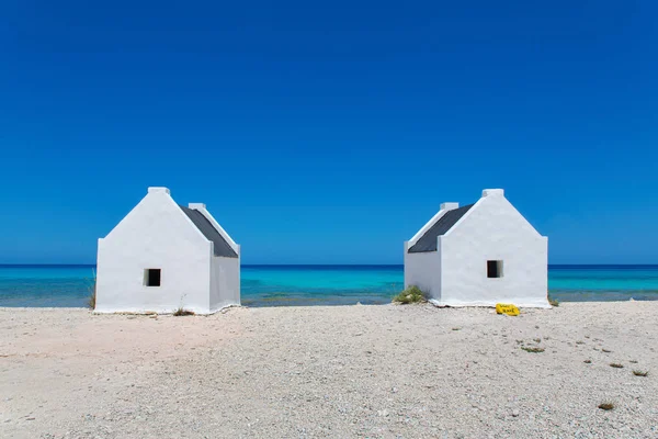 Kumsalda iki beyaz köle evi ve mavi deniz. — Stok fotoğraf