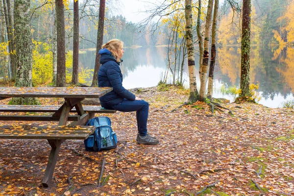 Mulher senta-se na mesa de piquenique na natureza finlandesa — Fotografia de Stock