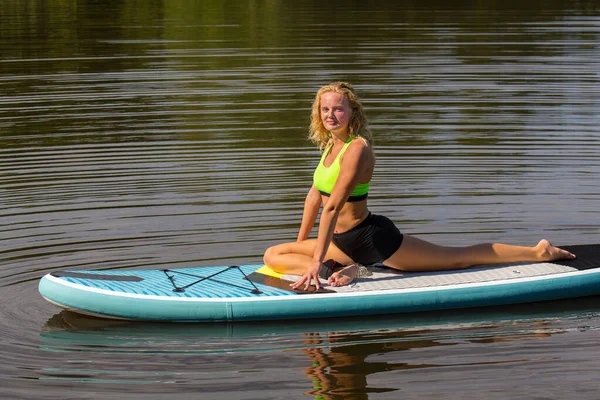 Jeune femme en posture de cygne de yoga sur SUP — Photo