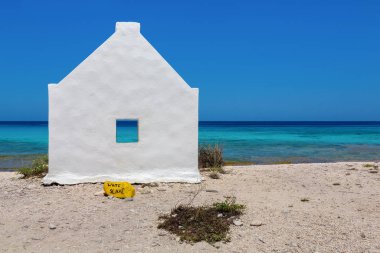 Kıyıda beyaz bir köle evi, Bonaire adasında mavi deniz.