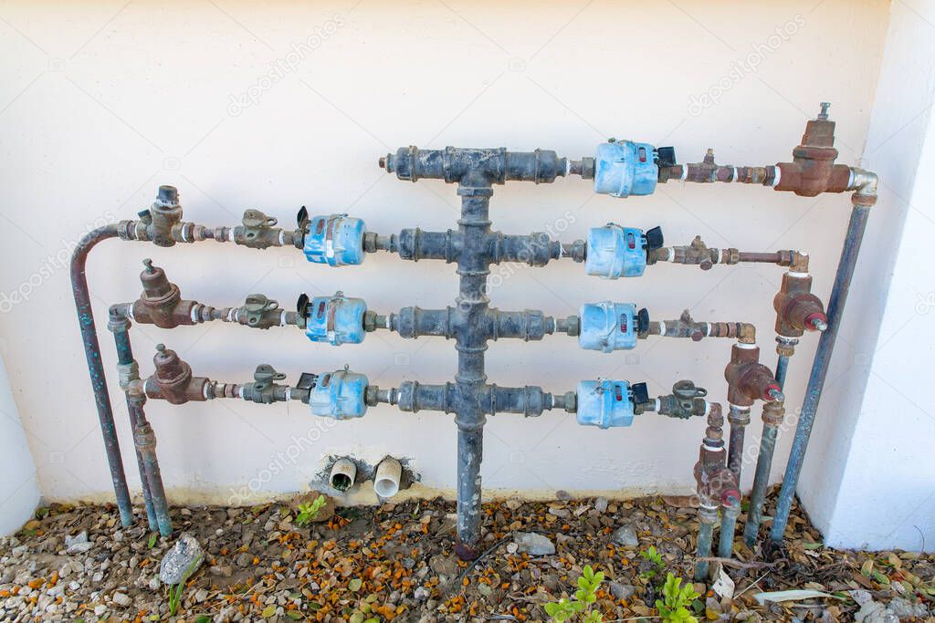 Water pipes with water taps and water meters on wall of house