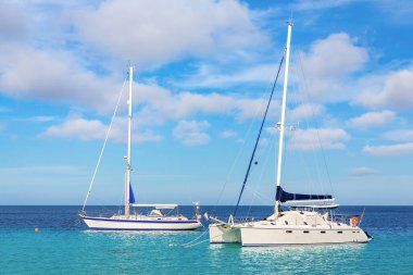 Bonaire kıyısında mavi sularda yüzen iki yelkenli.