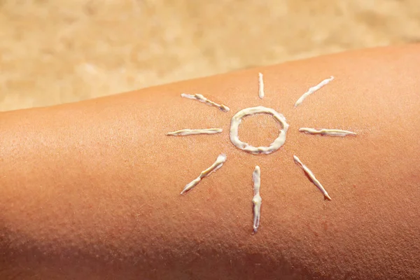 Drawn symbolic sun made of sun block on bare skin of female leg