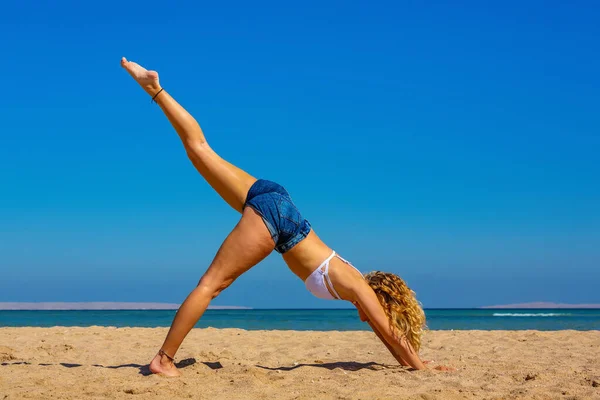 Young blonde woman in straight yoga posture on egyptian beach