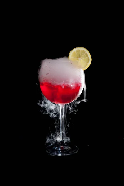 Kuru buz dumanı ve limon dilimi ile kırmızı soğuk kokteyl bir fincan