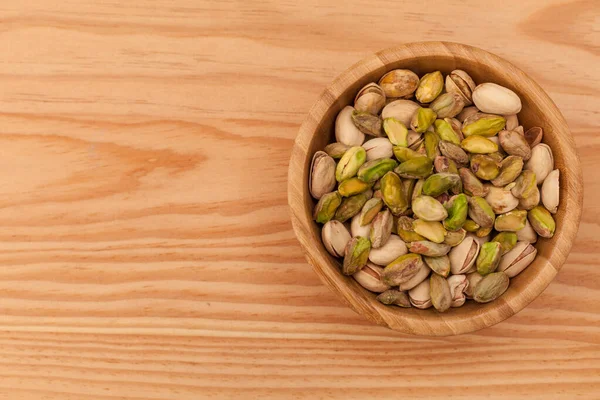 Vista superior de la cáscara y pistachos pelados en cuenco de madera . — Foto de Stock