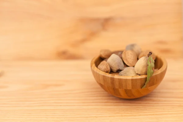 Almendras de concha en cuenco de madera sobre mesa de madera — Foto de Stock