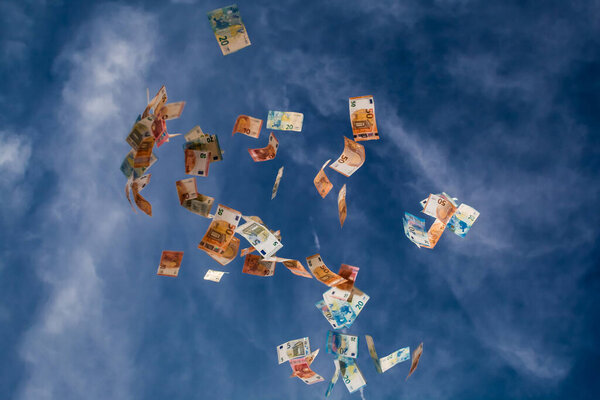 Falling money from the blue sky with clouds
